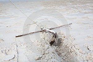 Small rusty traditional anchor on a beach by the sea