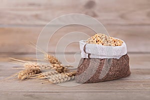 A small sack full of wheat and a few scattered ears of wheat