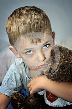 Small sad boy with eye bruise and teddy bear photo