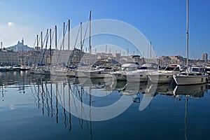 Small sail boats docking mooring in a row at Marseille old town harbor port on blue sky day with water reflection, Southern France