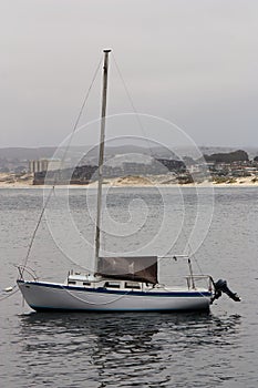 Small Sailboat Moored In Monterey Bay With Beach And Hills