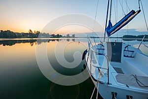 Small sailboat during sunrise are docking at Powidzkie lake in Poland