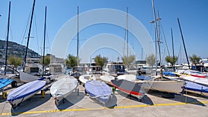 Small sailboats are docked on the port in the summer day