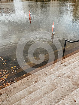 Small sailboats float in the lake next to a concrete staircase-descent.