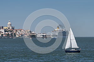 Small sailing boat in the Tagus River with the Lisbon skyline on the background