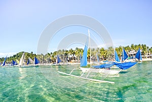 Small sailing boats for touristic excursions at sunset in Boracay island - Exclusive travel destination in Philippines - Vivid