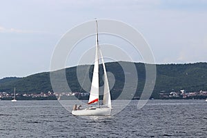 A small sailing sports yacht of daytime sailing is sailing with three yachtsmen along the coast of Croatia. Water sports and summe