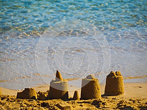Small sand castles near water on a small beach in Greece