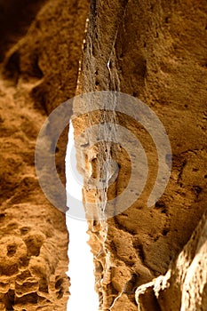 A small sandstone cave divided by huge cracks and illuminated by the sun. Close up sandstone texture background, natural