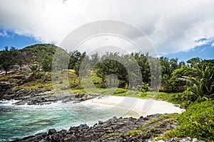 Small sandy beach between frozen lava flows of tropical volcanic