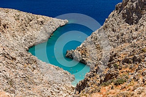 Small sandy beach with turquoise ocean hidden between tall cliffs in a narrow canyon Seitan Limania, Crete