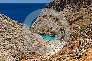 Small sandy beach with turquoise ocean hidden between tall cliffs in a narrow canyon Seitan Limania, Crete