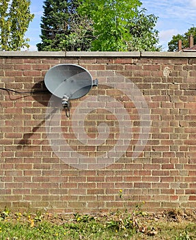 Small satellite tv dish mounted on exterior brick wall
