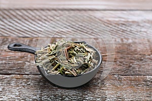 Small saucepan with aromatic dried lemongrass on wooden table. Space for text