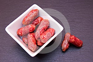 Small sausages on a square bowl on slate seen from above