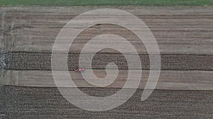 Small scale farming with red tractor plowing plow in field