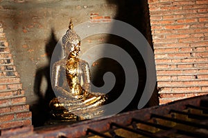 Small sculpture of Buddha with the offering of golden leaves wai phra at Ayutthaya, Thailand.