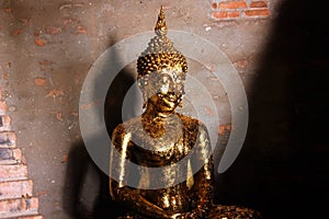 Small sculpture of Buddha with the offering of golden leaves wai phra at Ayutthaya, Thailand.