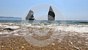 Small sea wave, blurred soft foamy waves washing golden sandy beach and volcanic rocky shores. Nobody. holiday