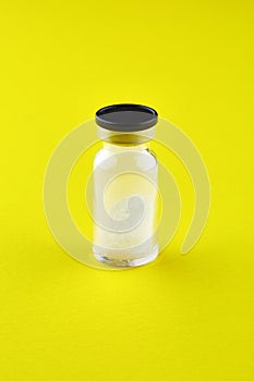 Small sealed bottle with medicine on yellow background