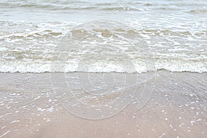 Small seaside waves near shoreline in sand