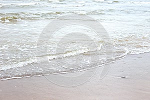 Small seaside waves near shoreline in sand