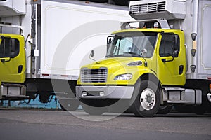 Small semi truck with box trailer and refrigeration unit for local delivery of food stand at warehouse dock for loading cargo