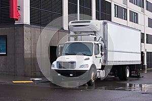 Small semi truck with reefer unit on box trailer for local delivery unloading delivered food