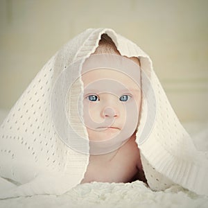 Small serious baby with Down syndrome hid under blanket