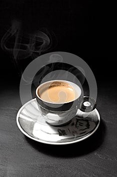 Small and shiny espresso cup with steaming hot coffee