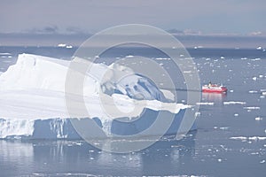 Small ship cruising among ice bergs during beautiful summer day. Disko Bay, Greenland.