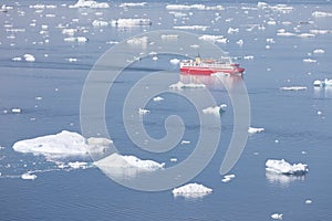 Small ship cruising among ice bergs during beautiful summer day. Disko Bay, Greenland