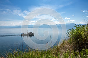 A small ship sails along the coast. Sunny summer day