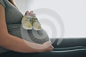 Small shoes in the belly of pregnant woman