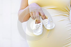 Small shoes for the unborn baby in the belly of a pregnant