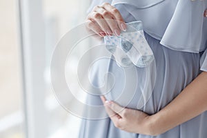 Small shoes for the unborn baby in the belly of pregnant woman