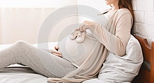 Small shoes for unborn baby on belly of pregnant woman