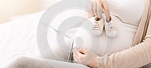 Small shoes for unborn baby on belly of pregnant woman