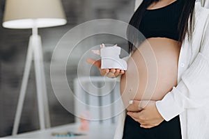 Small shoes for the unborn baby in the belly of pregnant woman