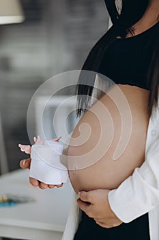 Small shoes for the unborn baby in the belly of pregnant woman