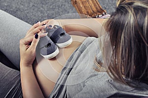 Small shoes for the unborn baby on the belly of pregnant woman