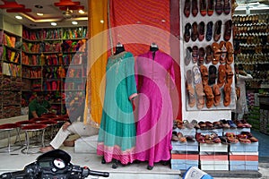 Small shop owner indian man selling shawls, clothing and souvenirs at his store. Colorful traditional Indian costume/outfit for