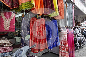 Small shop owner indian man selling shawls, clothing and souvenirs at his store. Colorful traditional Indian costume/outfit for
