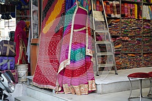 Small shop owner indian man selling shawls, clothing and souvenirs at his store. Colorful traditional Indian costume/outfit for