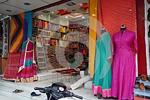 Small shop owner indian man selling shawls, clothing and souvenirs at his store. Colorful traditional Indian costume/outfit for