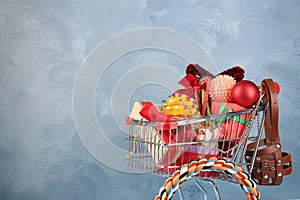 Small shopping cart with different pet goods and Christmas gifts on light blue background, space for text. Shop assortment