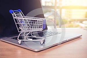Small shopping cart on Laptop for shopping online with sunny background, Technology business online concept.