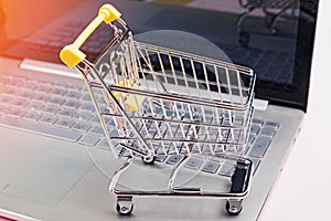 Small shopping trolley standing on laptop keyboard