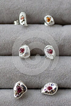 Small silver clumpy pebble-style stud earrings with gemstones  on a white background. photo