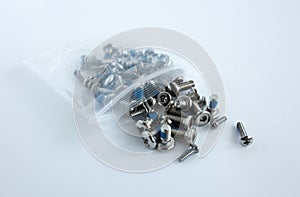 Small silver cogs on a white isolate. A plastic bag with screws for radio-controlled models. Chrome screws in a package